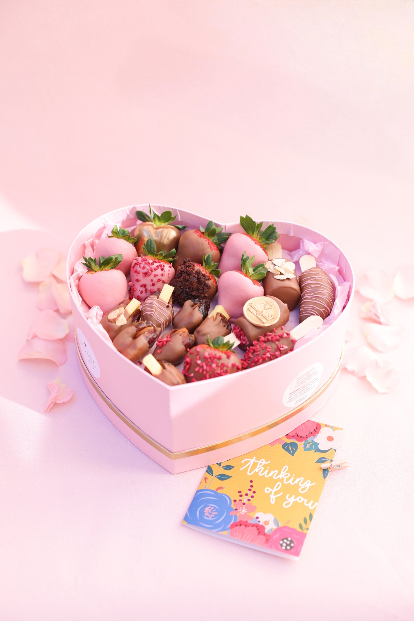 A beautifully arranged box filled with chocolate-covered strawberries, bananas, and dates, showcasing a delicious assortment of fresh fruits and Belgian chocolate.