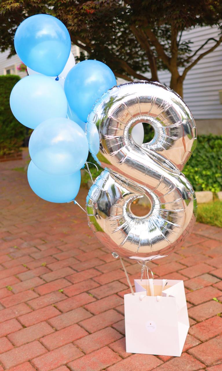 Festive balloon arrangement featuring a large number balloon with a bunch of colorful helium-filled balloon